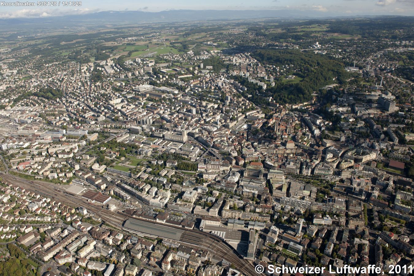 Lausanne, Blick nordwärts. Bildhintergrund rechts: Autobahnbrücke A9 über den Fluss 'Le Flon' nördlich an der bewaldeten Erhebung 'Bois de Sauvabelin' vorbei. Westlich daran anschliessend Hochhaussiedlung 'Borde de Bellevaux'. Weiter westlich (hintere Bildmitte): 'Stade Olympique de la Pontaise' (Position 2'537'549.15, 1'153'880.22). - Linke Bildseite, nördlich Bahnhof: Grünfläche 'Esplanade de Montbenon' (Position 2'537'667.86, 1'152'412.48).